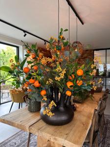 デルフトにあるHoeve BuytenHoutの木製テーブルの上に置かれたオレンジの入った黒い花瓶