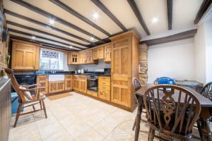 a kitchen with wooden cabinets and a table and chairs at Host & Stay - Well Farm Cottage in Higham