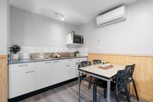 a kitchen with white cabinets and a table with chairs at Tasman Holiday Parks - Christchurch in Christchurch