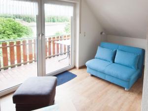 sala de estar con sofá azul y balcón en Komfortable Ferienwohnung mit Seeblick - b56594, en Bad Arolsen