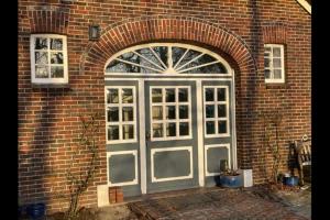 a brick building with a door with a window at Traumhaftes Reetdachhaus an der Nordsee in Süderschweiburg