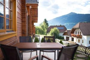 a wooden table and chairs on a balcony with a view at Charmantes Ferienhaus in Sankt Margarethen Im Lungau mit Kleinem Garten und Bergblick in Sankt Margarethen im Lungau