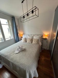 um quarto com uma cama com uma colcha branca em Appartement cosy, Bois de Vincennes-porte de Paris em Saint-Mandé