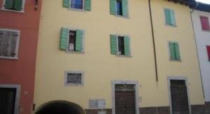 un edificio blanco con ventanas con contraventanas verdes en Schönes Appartement in Tiarno Di Sotto mit Garten, en Tiarno di Sotto