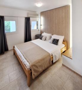 a bedroom with a large bed and two windows at Achlia Sea Side Retreat 1 in Ierápetra