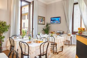 un ristorante con tavoli e sedie bianchi e finestre di Hotel Lombardi a Firenze