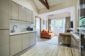 a kitchen with white cabinets and a living room at The Apartment Garth House in Brampton