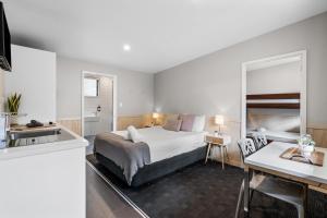 a bedroom with a bed and a kitchen with a sink at Tasman Holiday Parks - Christchurch in Christchurch