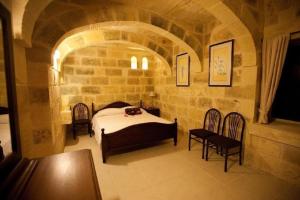 - une chambre en pierre avec un lit et des chaises dans l'établissement Villa Tina, à L-Għarb