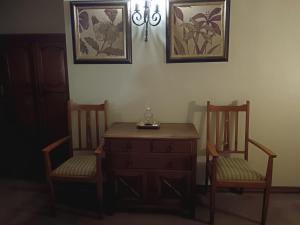 um quarto com duas cadeiras e uma cómoda e uma mesa e duas imagens em Inkungu Lodge em Champagne Valley