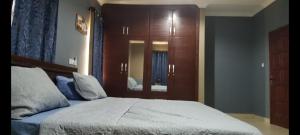 a bedroom with a large bed with a wooden cabinet at Stylish House with Generator - Tema Community 25 in Hanya