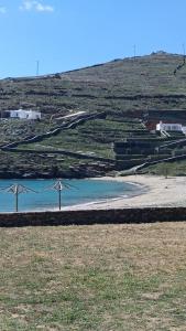 two windmills in a field next to a body of water at Simousi Studio 1, On the Beach! Kythnos in Kithnos