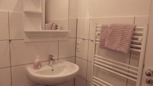 een witte badkamer met een wastafel en een handdoek bij Großzügige Ferienwohnung mit Privatgarten im Nordseebad Carolinensiel in Wittmund