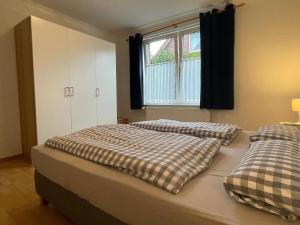 een slaapkamer met 2 bedden en een raam bij Großzügige Ferienwohnung mit Privatgarten im Nordseebad Carolinensiel in Wittmund