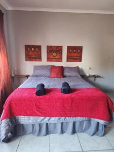 a bedroom with a large bed with a red blanket at Sweet Dreams Polokwane in Polokwane