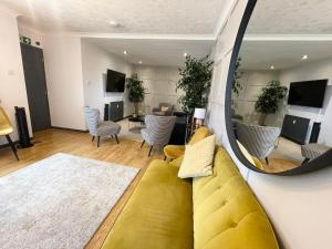 a living room with a yellow couch and a mirror at Bentinck Residence by Sasco Apartments, Lytham St Annes in Lytham St Annes