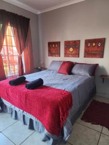 a bedroom with a large bed with a red blanket at Sweet Dreams Polokwane in Polokwane