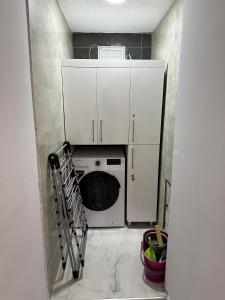 eine Waschküche mit einer Waschmaschine und weißen Schränken in der Unterkunft YUNUSELİ 7+2 VİLLA LUXURY in Yunuseli