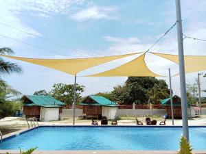 einen großen gelben Regenschirm über einem Pool in der Unterkunft Beachfront Mansion and Seascape Villas Calatagan with Outdoor Pool in Calatagan