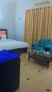 1 dormitorio con 1 cama, 1 silla azul y 1 mesa en Overseas B&B Guest House en Islamabad