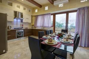 een eetkamer met een tafel en stoelen en een keuken bij Villa Cara in Għarb