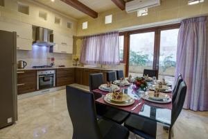Un comedor con mesa y sillas y una cocina. en Villa Cara, en Għarb