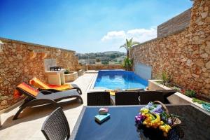 een patio met een zwembad en een tafel en stoelen bij Villa Cara in Għarb