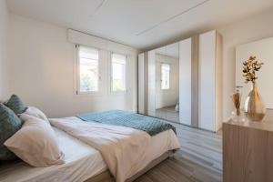 a white bedroom with a large bed and two windows at Apartment deluxe ground floor Venice/Treviso park in Silea