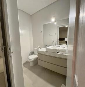 bagno con servizi igienici, lavandino e specchio di Gontijo Apart Hotel a Itajubá