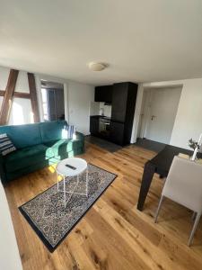 ein Wohnzimmer mit einem grünen Sofa und einem Tisch in der Unterkunft Stilvolle 2,5 Zimmer Wohnung in St. Gallen