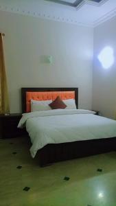 1 dormitorio con 1 cama grande y cabecero naranja en Overseas B&B Guest House en Islamabad