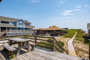 a wooden deck with a picnic table and a house at NH222 Island Dancer in Nags Head
