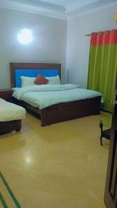 1 dormitorio con 2 camas y cortina verde en Overseas B&B Guest House en Islamabad