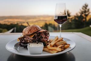 a plate with a sandwich and french fries and a glass of wine at Hotel Monínec in Moninec