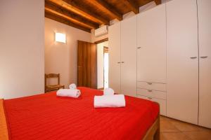 - une chambre avec un lit rouge et 2 serviettes dans l'établissement Ferienwohnung in Moniga Del Garda mit gemeinsamem Pool und Garten und Seeblick, à Moniga del Garda