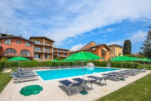 - une piscine avec des chaises et des parasols verts dans l'établissement Ferienwohnung in Moniga Del Garda mit gemeinsamem Pool und Garten und Seeblick, à Moniga del Garda