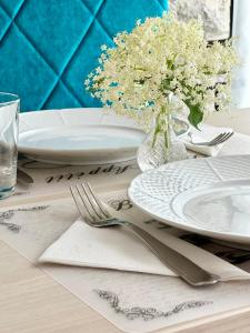 une table avec des assiettes, des fourchettes et un vase de fleurs dans l'établissement Éllő Residence, à Veszprém