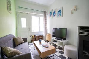 een woonkamer met een bank en een tv bij Escapade au Roc de Picchu in Étretat