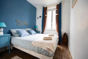 een blauwe slaapkamer met een bed met twee handdoeken erop bij Escapade au Roc de Picchu in Étretat