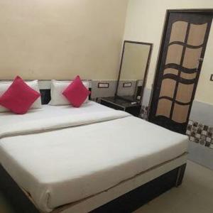 un letto con due cuscini rossi in una stanza di RESIDENCE TULSI a Vrindāvan