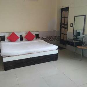 a bedroom with a bed with red pillows and a mirror at RESIDENCE TULSI in Vrindāvan