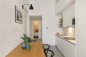 a kitchen with white walls and a wooden table and chairs at Candelaria10 in Cádiz