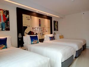 a hotel room with two beds and a poster on the wall at Hotel Clover Asoke - SHA Extra Plus in Bangkok