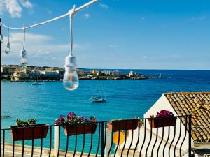 einen Balkon mit Blumen und Blick auf das Wasser in der Unterkunft Dimora del Sole Luxury and charm apartment in Otranto