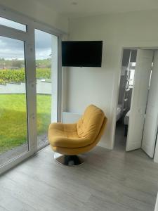uma sala de estar com uma cadeira amarela e uma televisão em Chalet with sea views em Ballyshannon