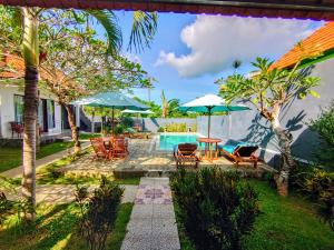 a backyard with a pool and chairs and umbrellas at Tunjung Kuning Cottage in Nusa Penida