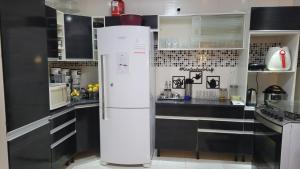 a white refrigerator in a kitchen with black cabinets at Casa Temporada Garanhuns in Garanhuns