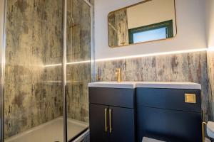 La salle de bains est pourvue d'un lavabo, d'une douche et d'un miroir. dans l'établissement Guest Homes - Foregate Studio Apartment, à Worcester