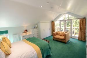 a bedroom with a bed and a chair and a window at The Gardeners Cottage, Hutton John is a luxurious cottage with hot tub 10 minutes from Lake Ullswater in Penruddock