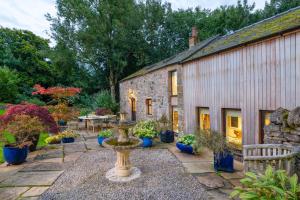 a garden with a fountain in front of a stone building at The Gardeners Cottage, Hutton John is a luxurious cottage with hot tub 10 minutes from Lake Ullswater in Penruddock